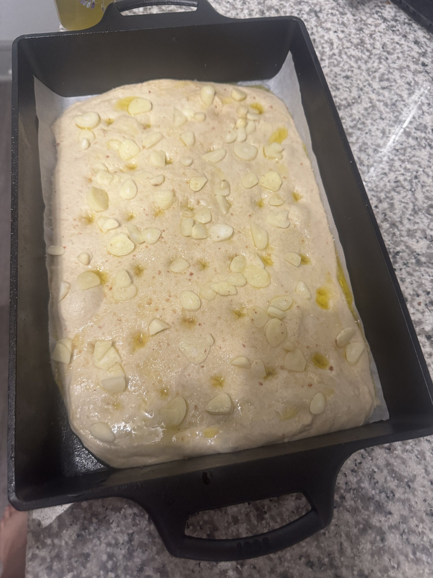 Dimpled, oiled, and topped with salt and sliced garlic.